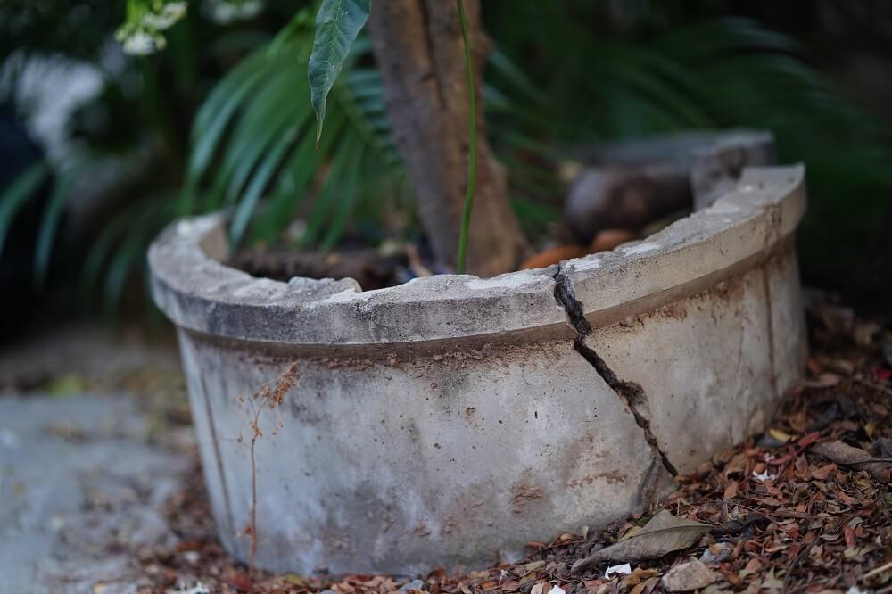 Large concrete planter with a deep crack running down from the rim