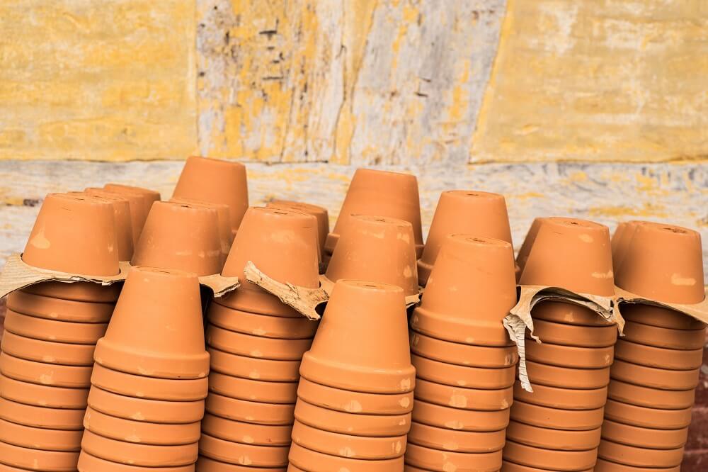 Empty terracotta pots stacked upside down with cardboard between some rims